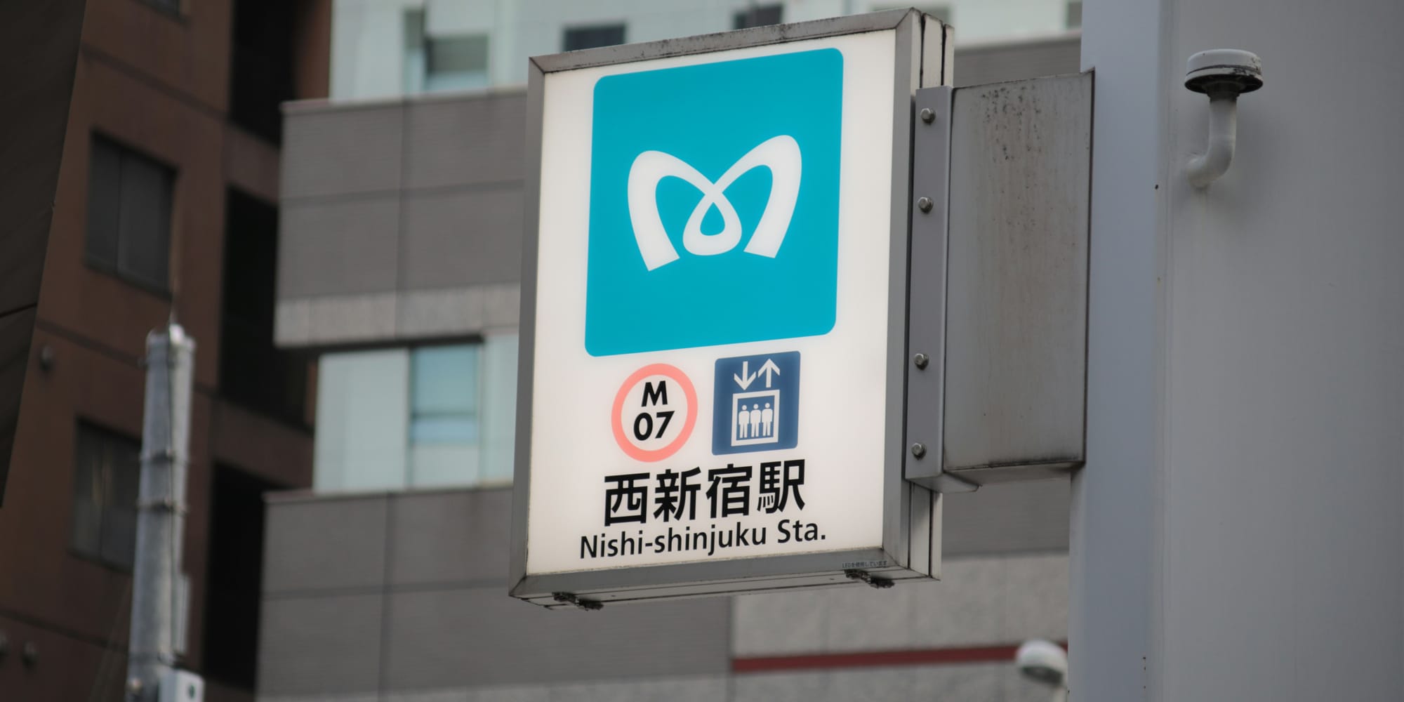 Tokyo Metro station sign for Nishi-Shinjuku Station (M-07) on the Marunouchi Line, showing Tokyo Metro's teal corporate logo, the station number, and the station name in Japanese and English