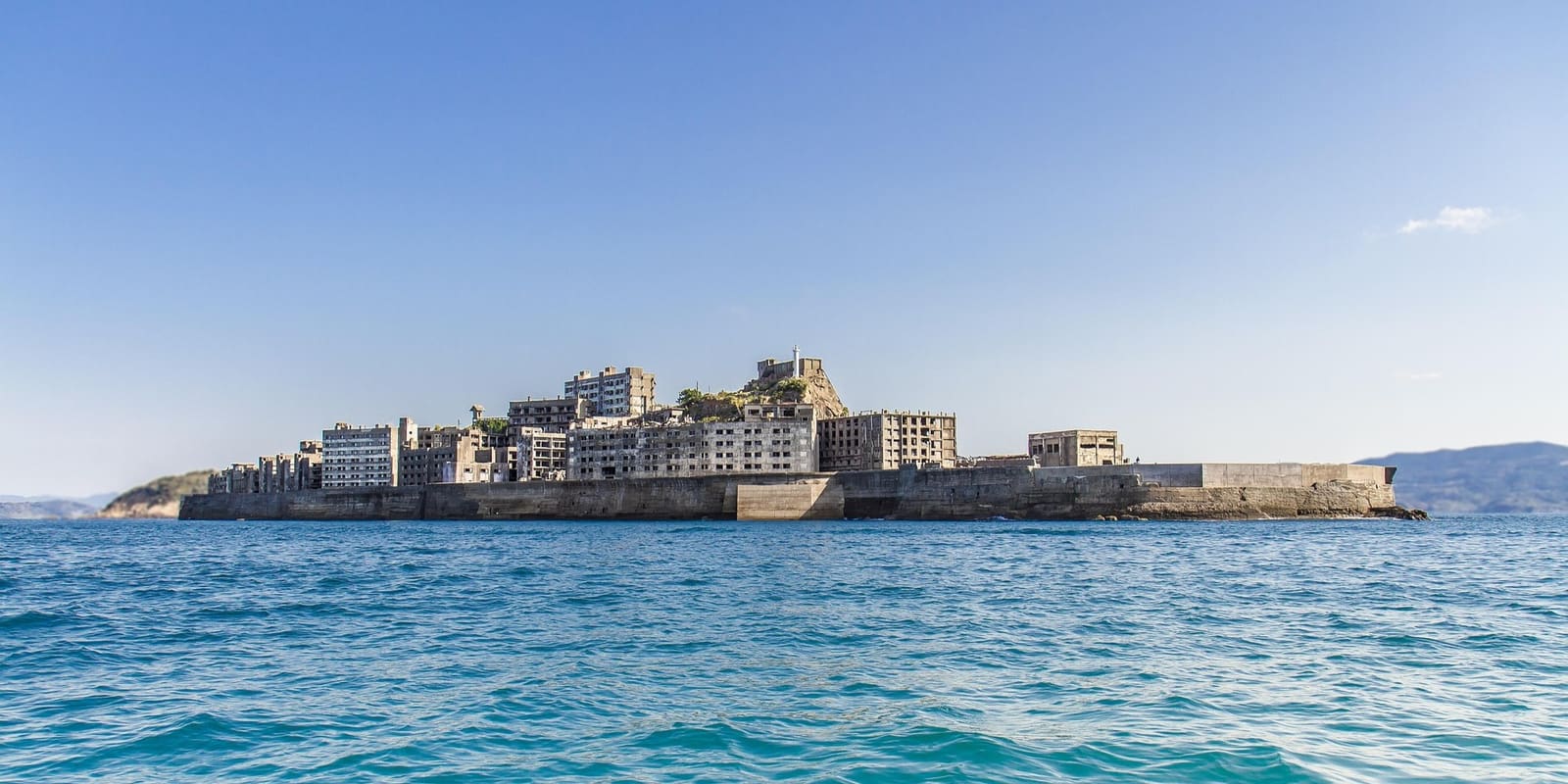 Abandoned concrete apartment blocks and the encircling sea wall of Gunkanjima (Hashima Island) off the coast of Nagasaki, Japan