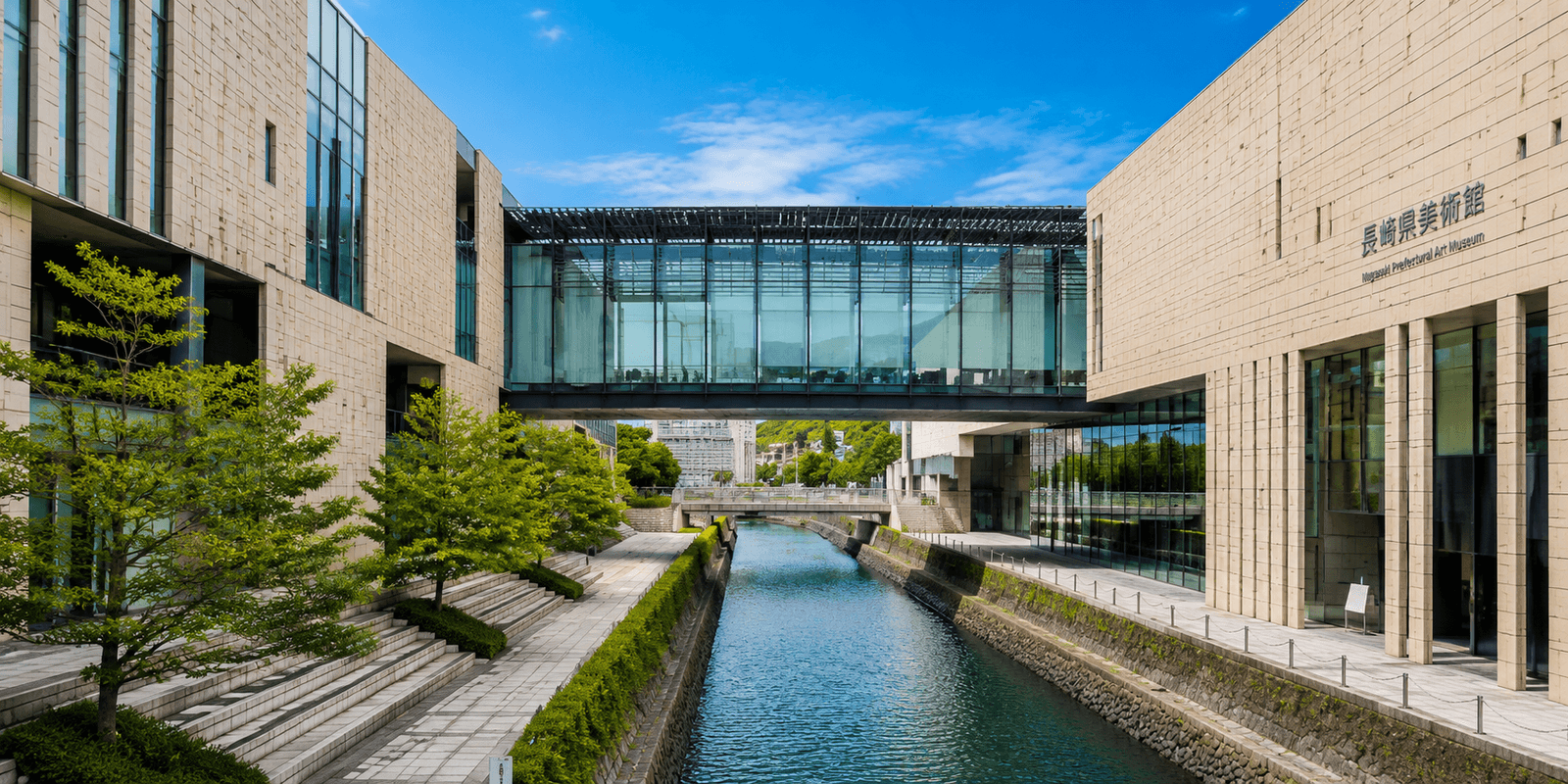 Glass-walled twin buildings of the Nagasaki Prefectural Art Museum bridged above a canal in Dejima-machi, Nagasaki, Japan