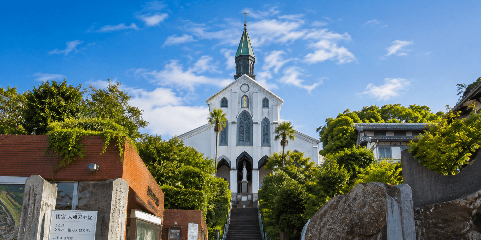 White Gothic facade and spire of Oura Cathedral above its stone approach in Minamiyamate, Nagasaki
