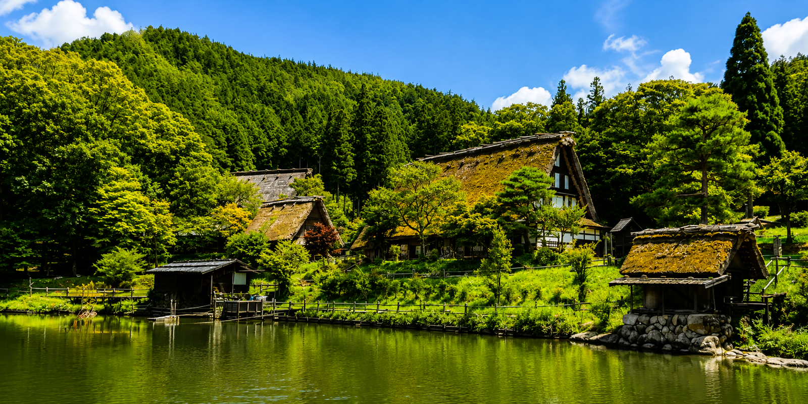 Thatched gassho-zukuri farmhouses of Hida Folk Village reflected in the central pond, Takayama, Japan