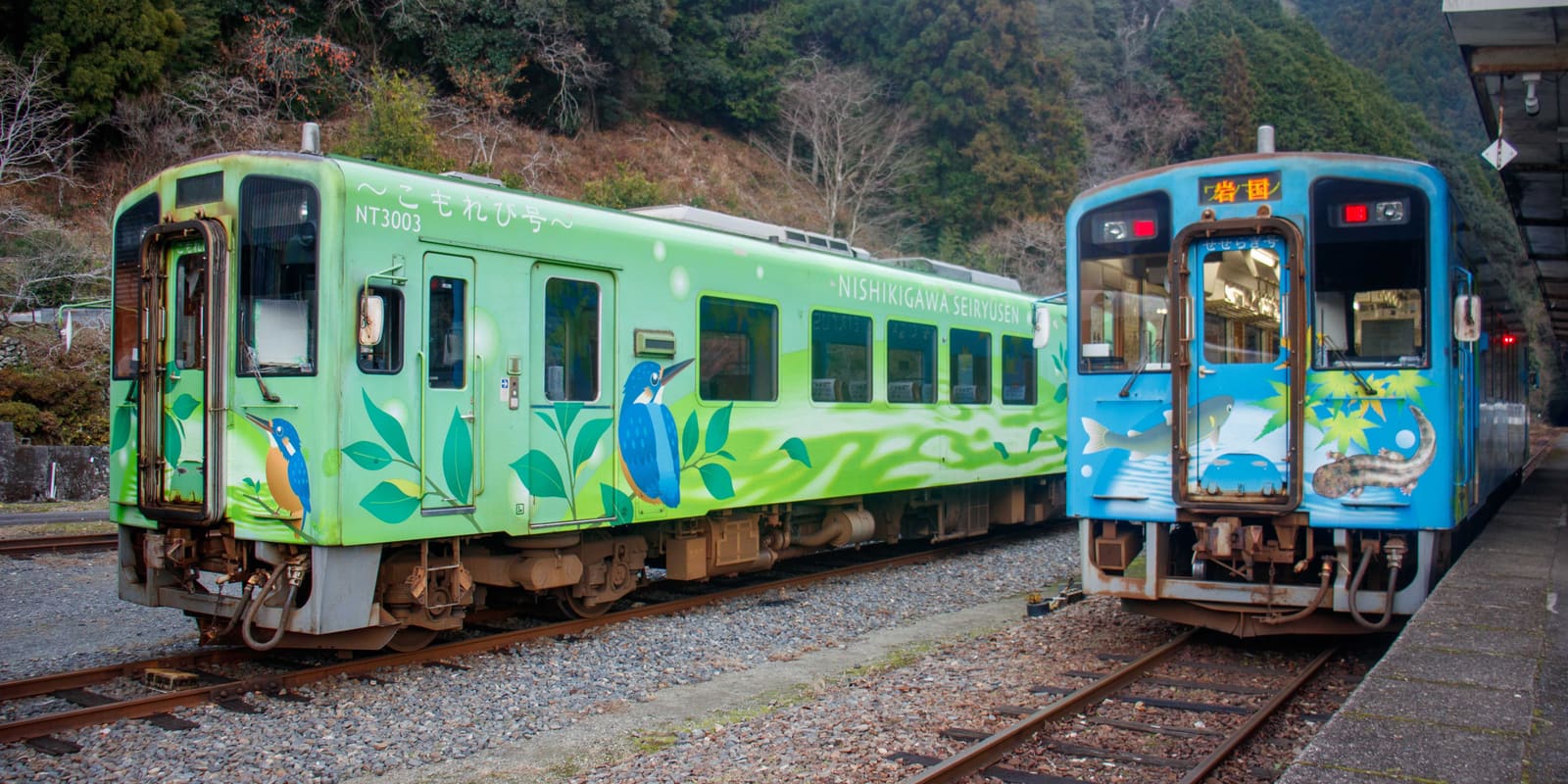 Two colorful local trains at a rural station in Japan