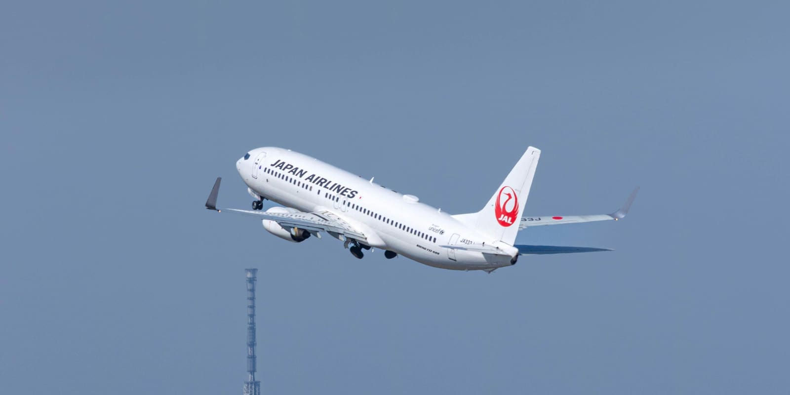 A Japan Airlines Boeing 737-800 climbing after takeoff against a clear blue sky
