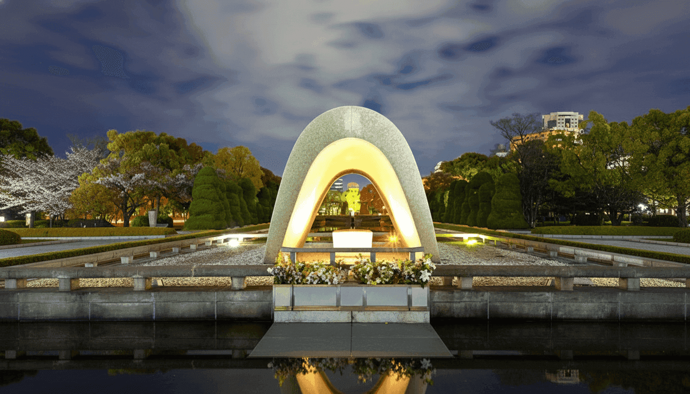 Hiroshima Peace Memorial cenotaph illuminated at night with reflecting pool and surrounding cherry trees, Japan
