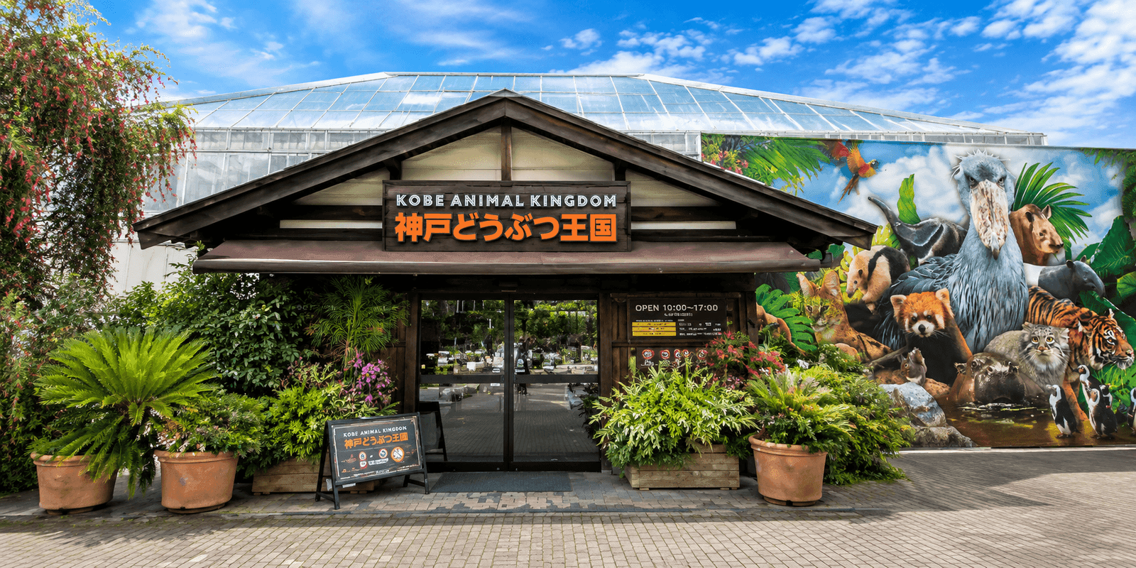 Storefront entrance of Kobe Animal Kingdom with a glasshouse roof and animal mural on Port Island in Kobe