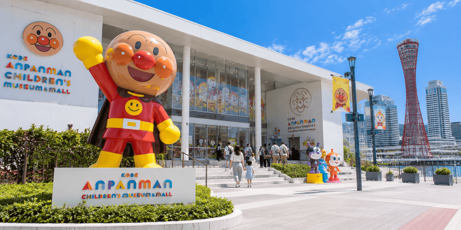 Entrance of Kobe Anpanman Children's Museum & Mall with a large Anpanman statue and Kobe Port Tower in the background