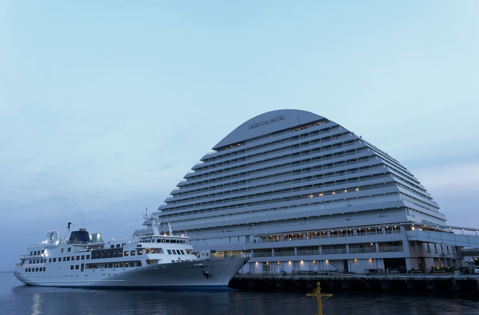 The Kobe Meriken Park Oriental Hotel and a docked sightseeing ship on the Meriken Park waterfront at dusk