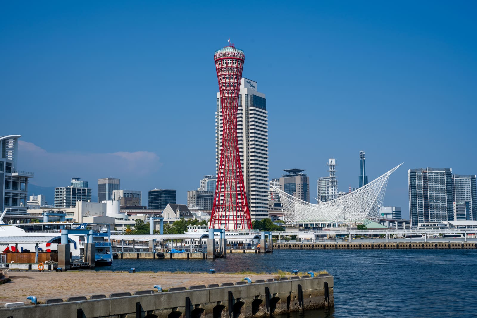 Red lattice Kobe Port Tower rising above Meriken Park harbor in Kobe Japan