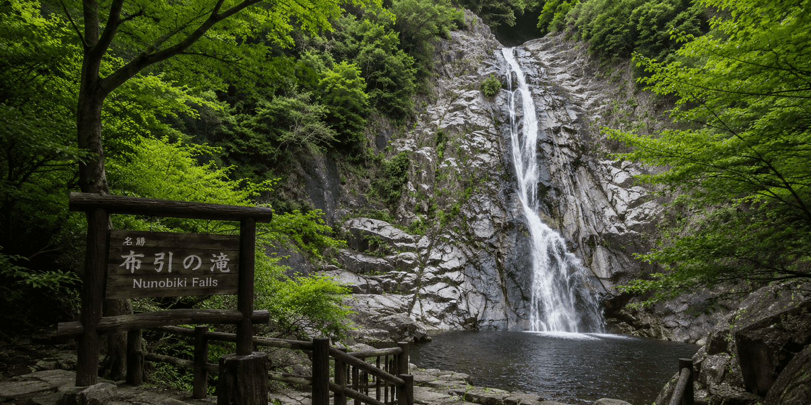 Ontaki, the tallest of the four Nunobiki Falls, cascading into a pool beside a wooden trail sign in Kobe