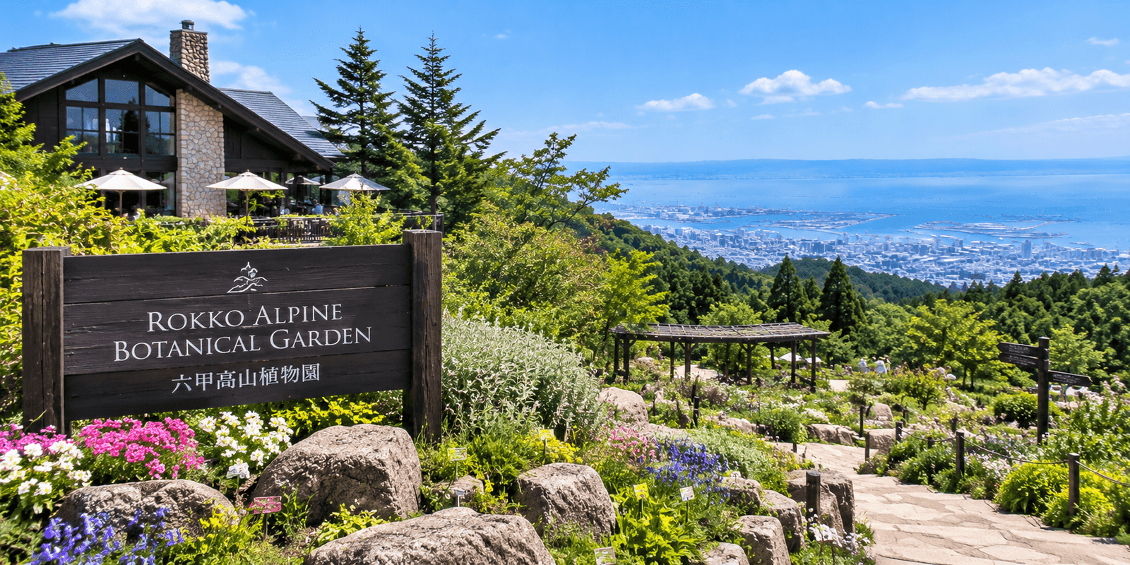 Flowering alpine plants and the entrance sign at Rokko Alpine Botanical Garden with a view over Kobe and Osaka Bay