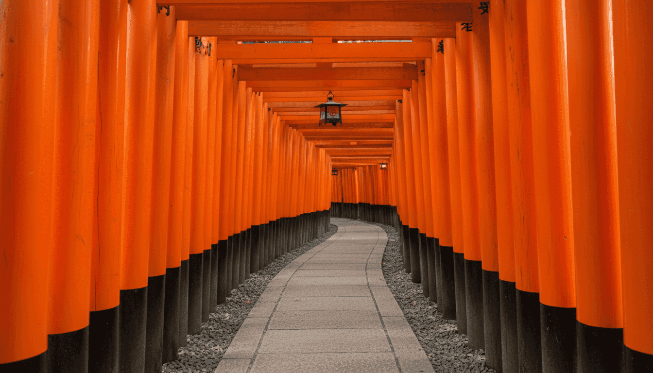 A stone path through a tunnel of closely spaced vermilion torii at Fushimi Inari Taisha