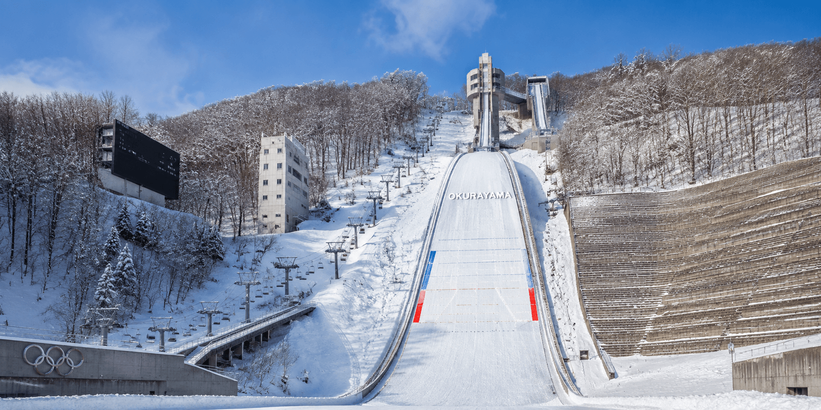 Snow-covered Okurayama ski jump hill with chairlift and Olympic rings monument in Sapporo Japan