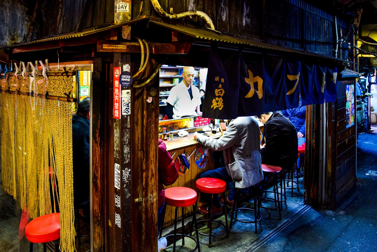 Omoide Yokocho narrow alleyway in Shinjuku lined with glowing red lanterns and small yakitori restaurants at night, Tokyo
