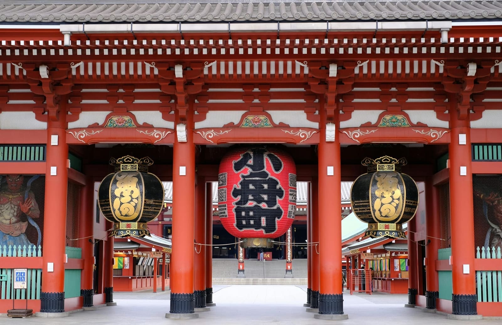Close-up of Hozomon Gate at Senso-ji showing red pillars, ornate lanterns, and guardian statue murals