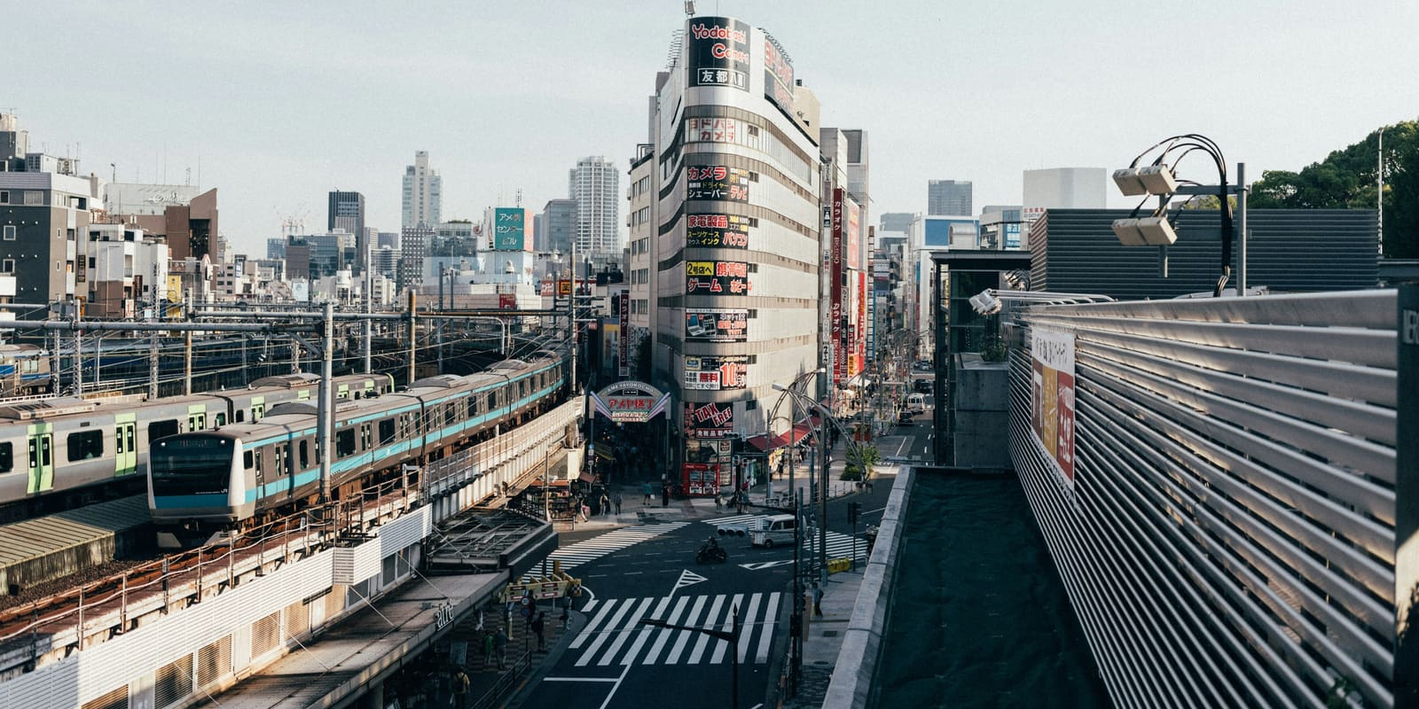 A JR commuter train running on the elevated tracks beside Ueno shopping streets