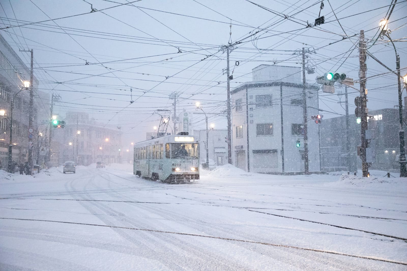 A snow-covered tram making its way through a heavy snowstorm in Sapporo