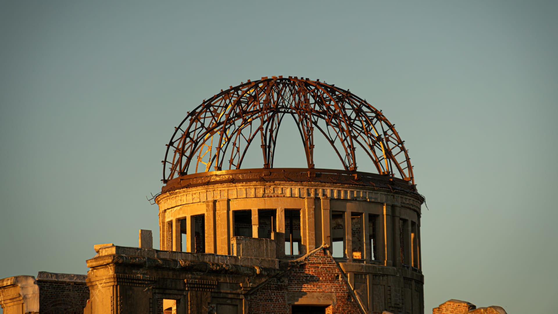 Atomic Bomb Dome skeletal iron dome frame glowing in warm golden light at sunset, Hiroshima Japan