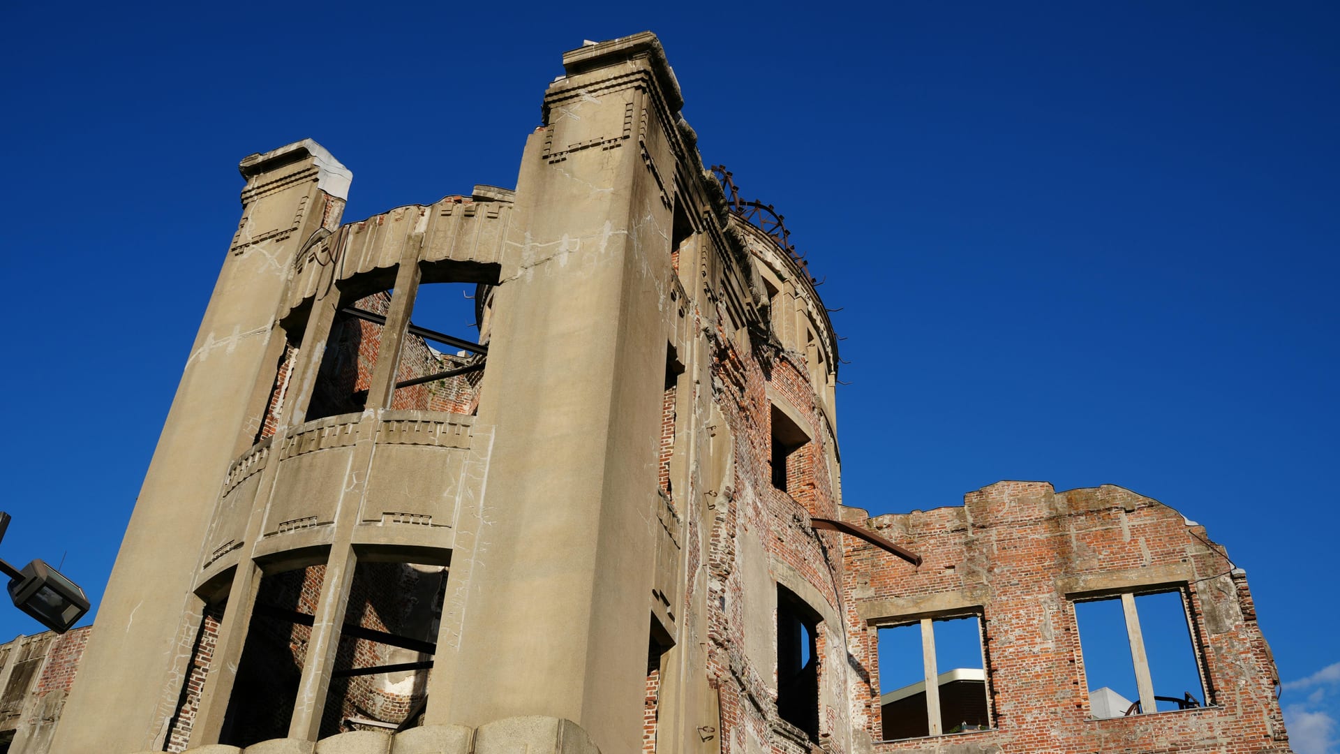 Atomic Bomb Dome exterior walls and exposed brick structure seen from ground level against a bright blue sky, Hiroshima Japan