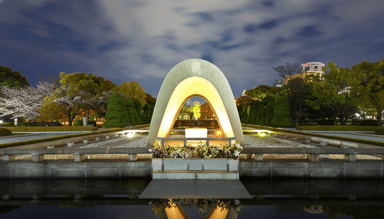 Hiroshima Peace Memorial cenotaph illuminated at night with reflecting pool and surrounding cherry trees, Japan