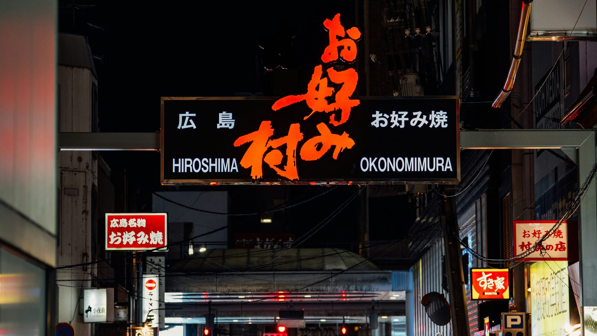 Hiroshima Okonomimura illuminated entrance sign at night above the okonomiyaki building, Japan