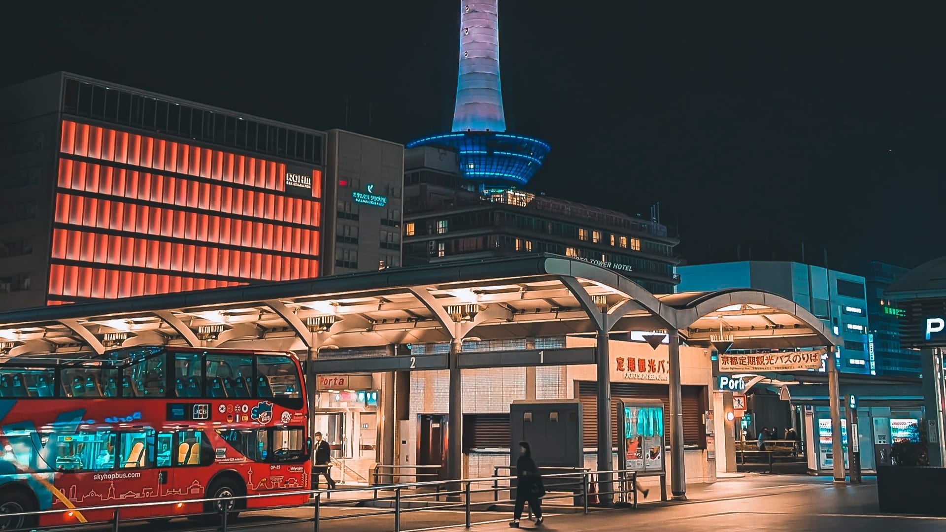 Kyoto Tower glowing at night with Kyoto Station and the city skyline spread below