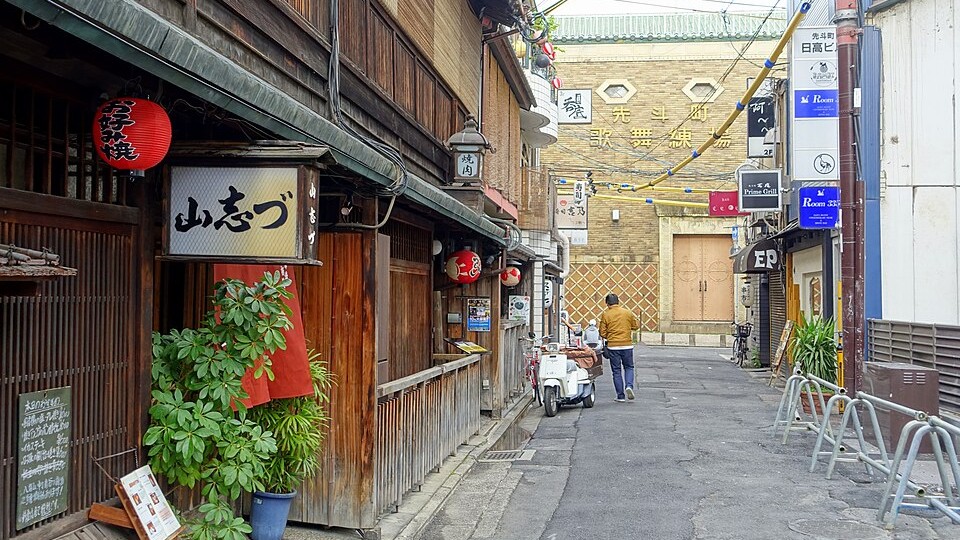 Narrow lantern-lit alley of Pontocho at dusk with glowing restaurant facades