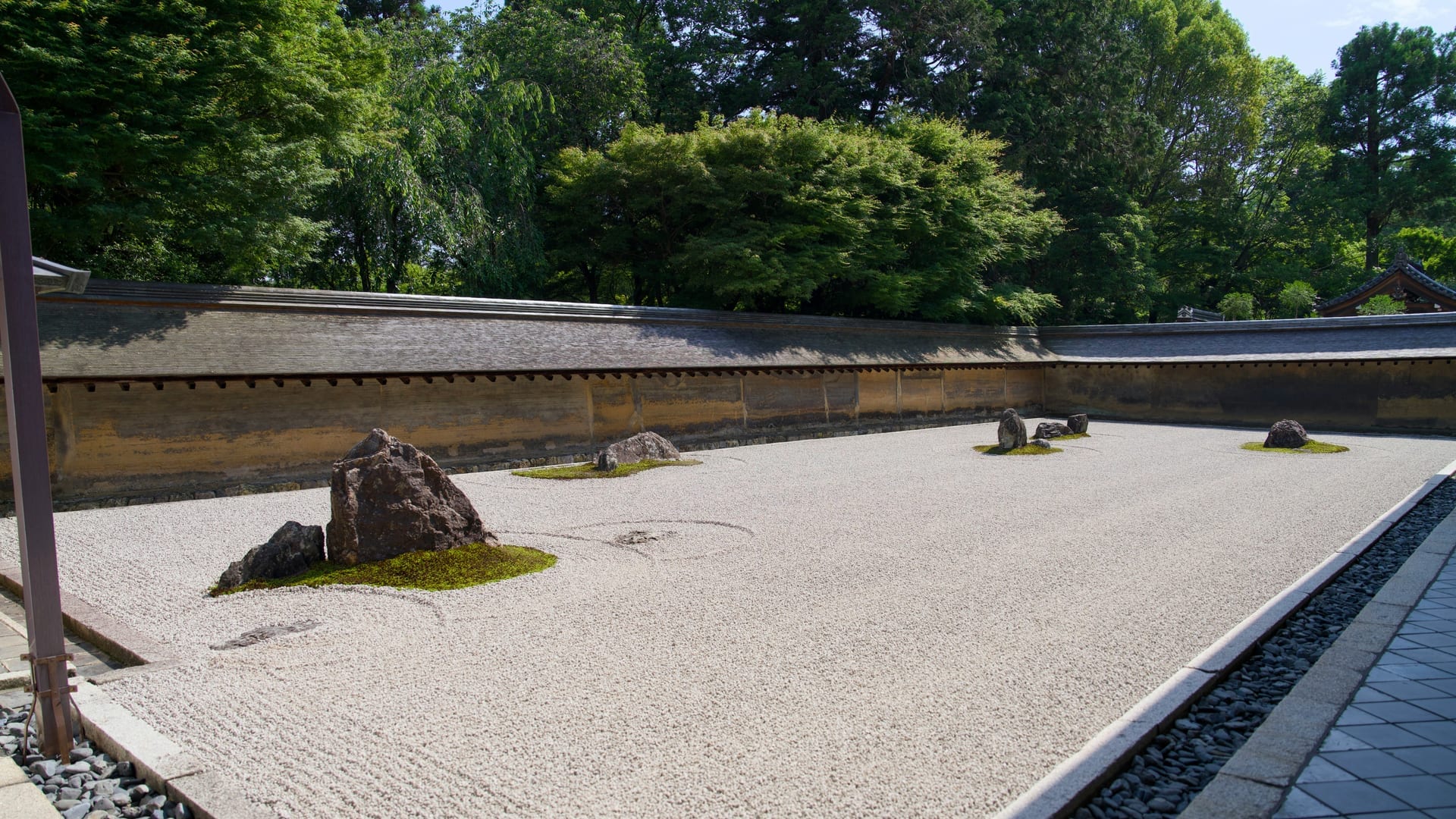 Wooden veranda overlooking the Ryoan-ji rock garden with earthen walls and stone arrangement