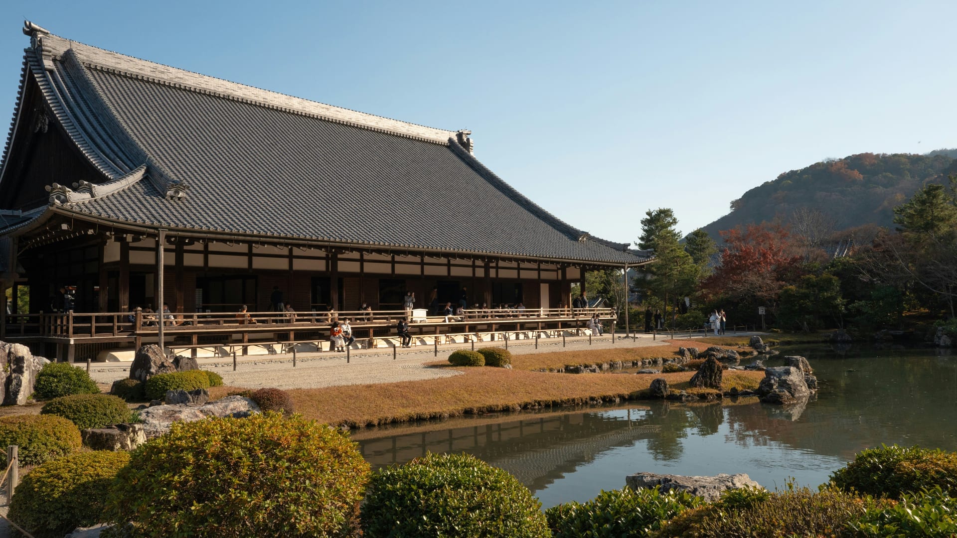 Sogenchi Garden reflecting pond at Tenryu-ji with stone arrangements and pine trees against the Arashiyama hills