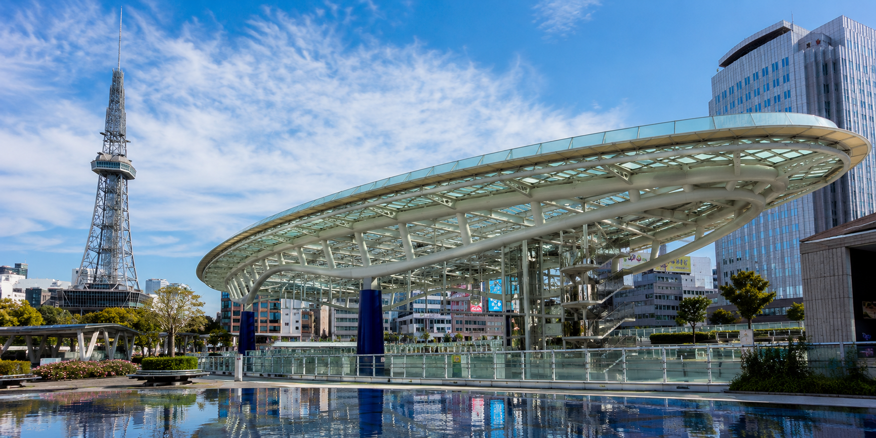 Daytime view of Oasis 21's glass 'Spaceship Aqua' rooftop reflected in its water basin, with MIRAI TOWER visible in the background in Nagoya's Sakae district