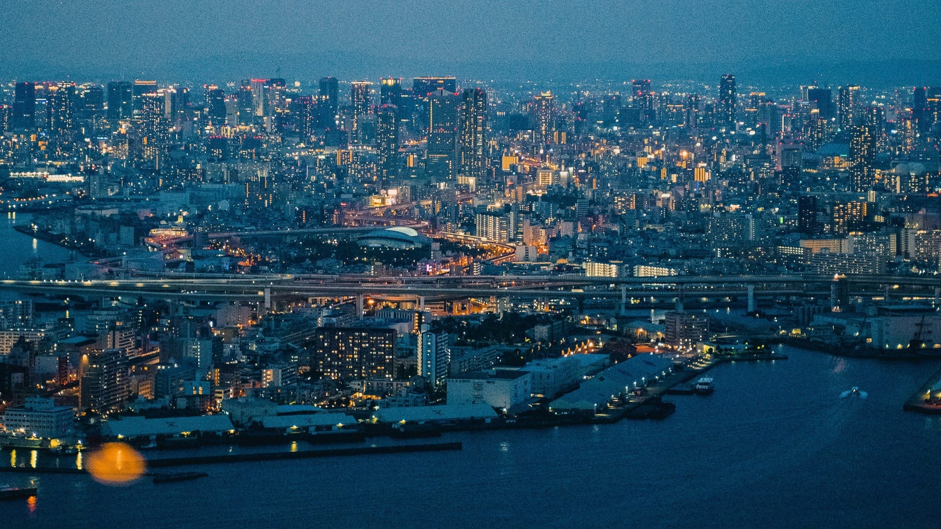 Osaka Bay evening harbor view with city skyline reflections, ferries, and waterfront lights at sunset, Japan