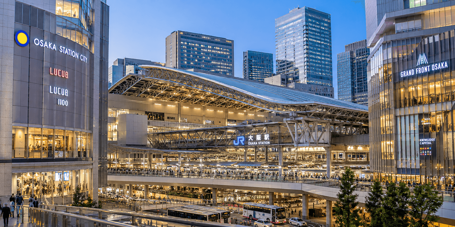 Osaka Station City's branded signage on the LUCUA building beside JR Osaka Station's domed roof and Grand Front Osaka at dusk, Japan