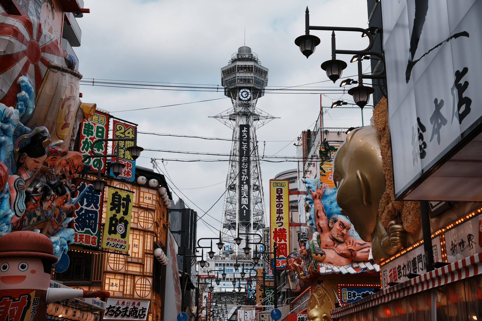 Shinsekai district at night with Tsutenkaku Tower lit up and retro neon signs along the narrow streets, Osaka Japan