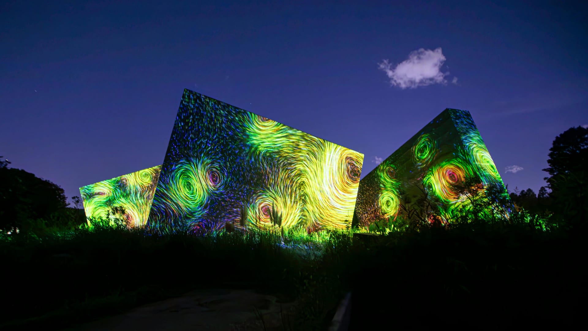 teamLab Botanical Garden Osaka large geometric structures covered with swirling green digital light projections against a night sky, Japan